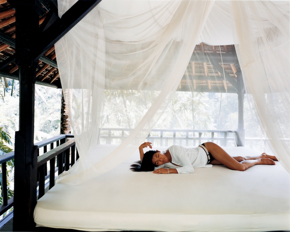 Asian girl on the white bed in an open to nature wooden room