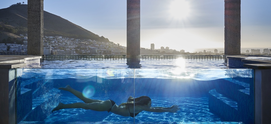 See-through pool with a girl and Table Mountain panorama at The Silo Hotel