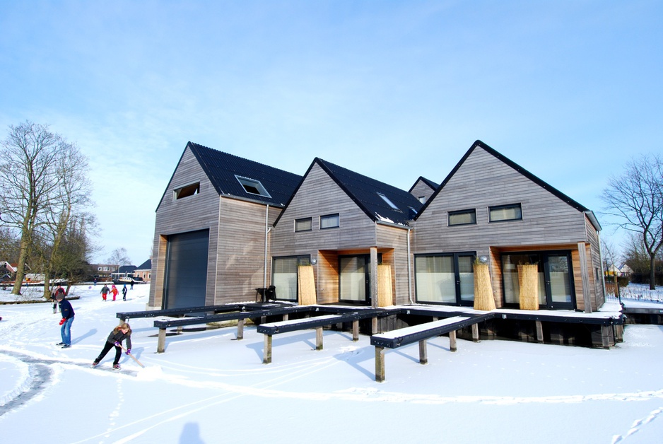 Ice-skating on frozen river in front of Werf Ijlst wooden lodge