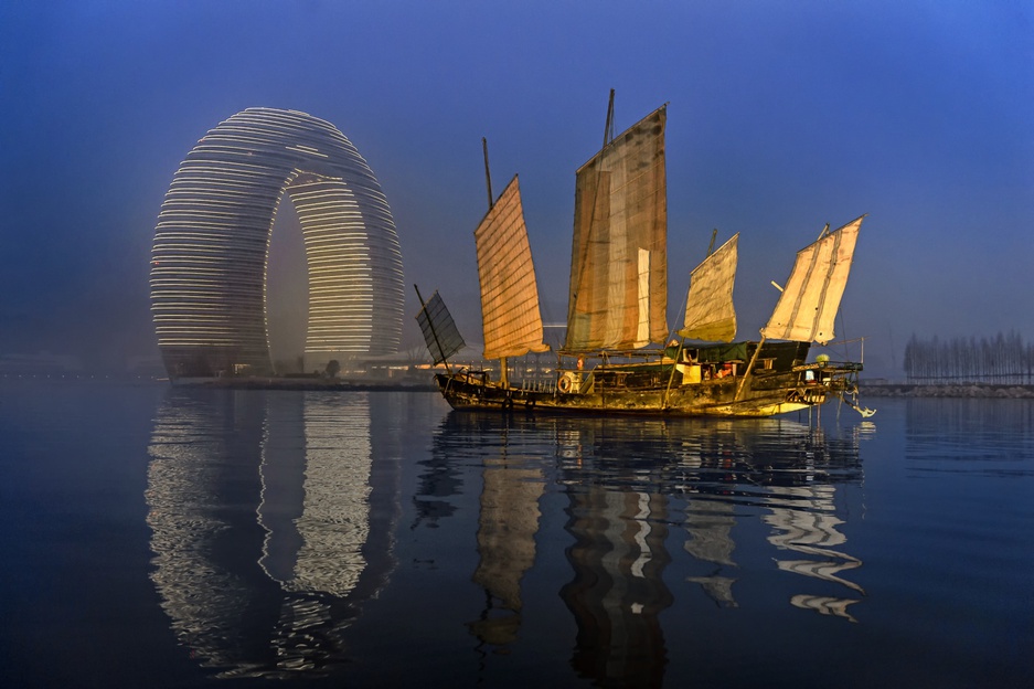 Sheraton Huzhou Hot Spring Resort at night and an old sailing boat on the sea