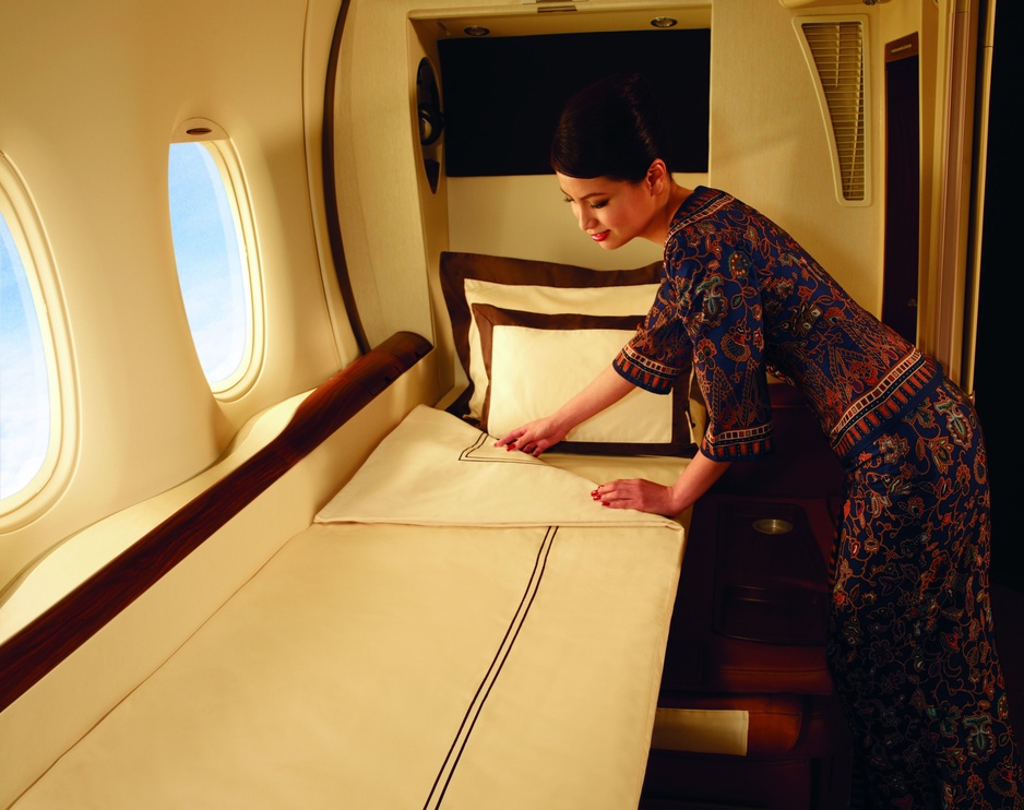 Singapore Airlines stewardess makes the bed in the luxury suite cabin