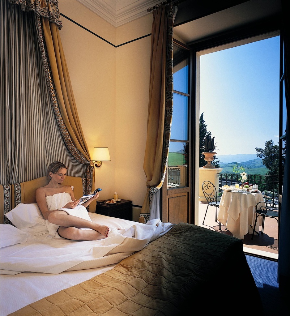 Girl in a towel on the bed reading newspaper in the room of Fonteverde hotel