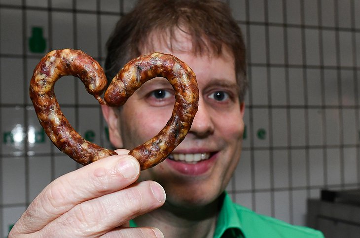 Claus Böbel, the owner of Bratwurst Hotel with a sausage in his hand